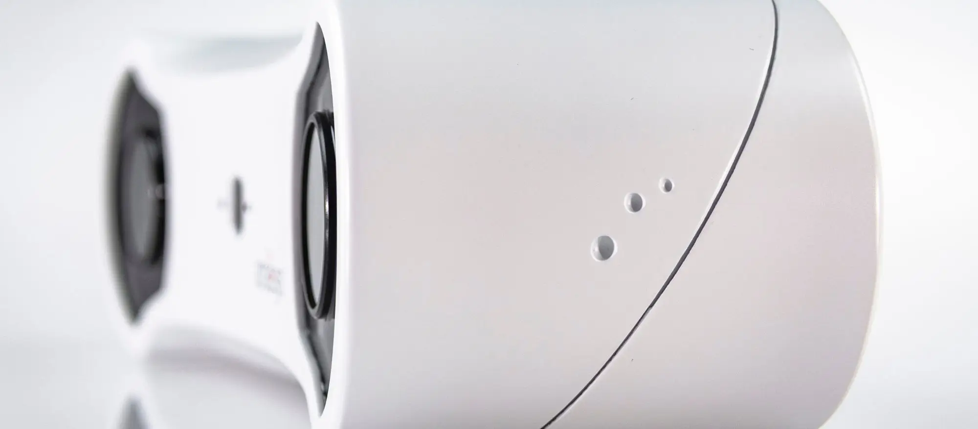 Close-up of a sleek, modern white electronic device with smooth curves, three small circular holes, and a visible black circular component on the left side—a perfect example of a balanced tracking solution. The background is white and out of focus.